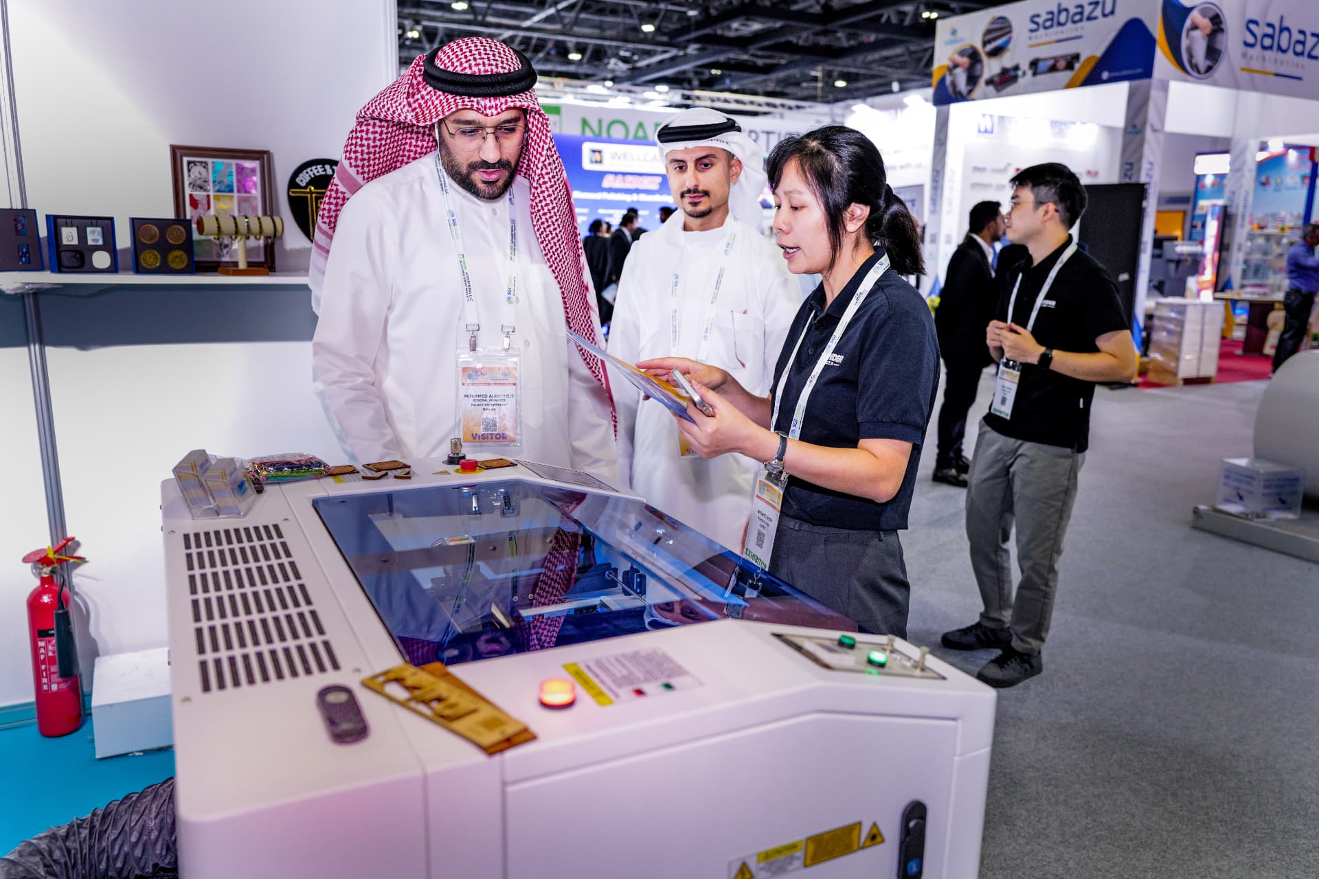 Visitor discussing a laser engraving machine with an exhibitor at SGI MENA
